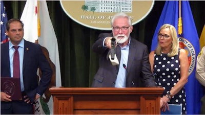 Lancaster Mayor Rex Parris picks up one of 33 confiscated firearms—from a widescale operation involving $1.2 billion of illegal cannabis in Southern California—and points it in the direction of media members during a press conference July 7 in Los Angeles County. “And if you have any doubt, our citizens have to look at this part of the gun; not this part,” he said.
