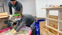 Homeland Hempcrete’s Matt Marino pouring hemp hurd into a water and lime mixture as the business’ Sam Marino, Matt’s wife, mixes it all together.