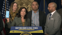 Gov. Kathy Hochul holds up a phone showing map locations of unlicensed cannabis shops in New York that appear in a search engine.