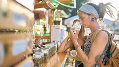 Two female tourists shopping for marijuana at a legal cannabis shop in Pattaya, Thailand, and smelling product.