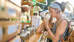 Two female tourists shopping for marijuana at a legal cannabis shop in Pattaya, Thailand, and smelling product.