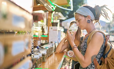 Two female tourists shopping for marijuana at a legal cannabis shop in Pattaya, Thailand, and smelling product.