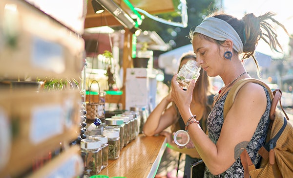 Two female tourists shopping for marijuana at a legal cannabis shop in Pattaya, Thailand, and smelling product.
