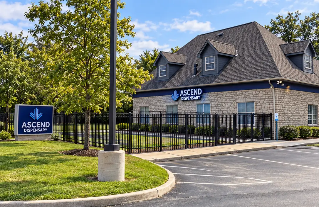Ascend Dispensary brick building exterior with logo sign, black fence, and landscaping