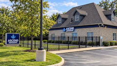 Ascend Dispensary brick building exterior with logo sign, black fence, and landscaping
