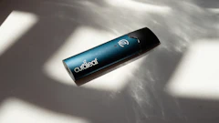 Curalear branded cylindrical device with teal finish and white logo symbol on white surface with shadows