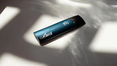 Curalear branded cylindrical device with teal finish and white logo symbol on white surface with shadows
