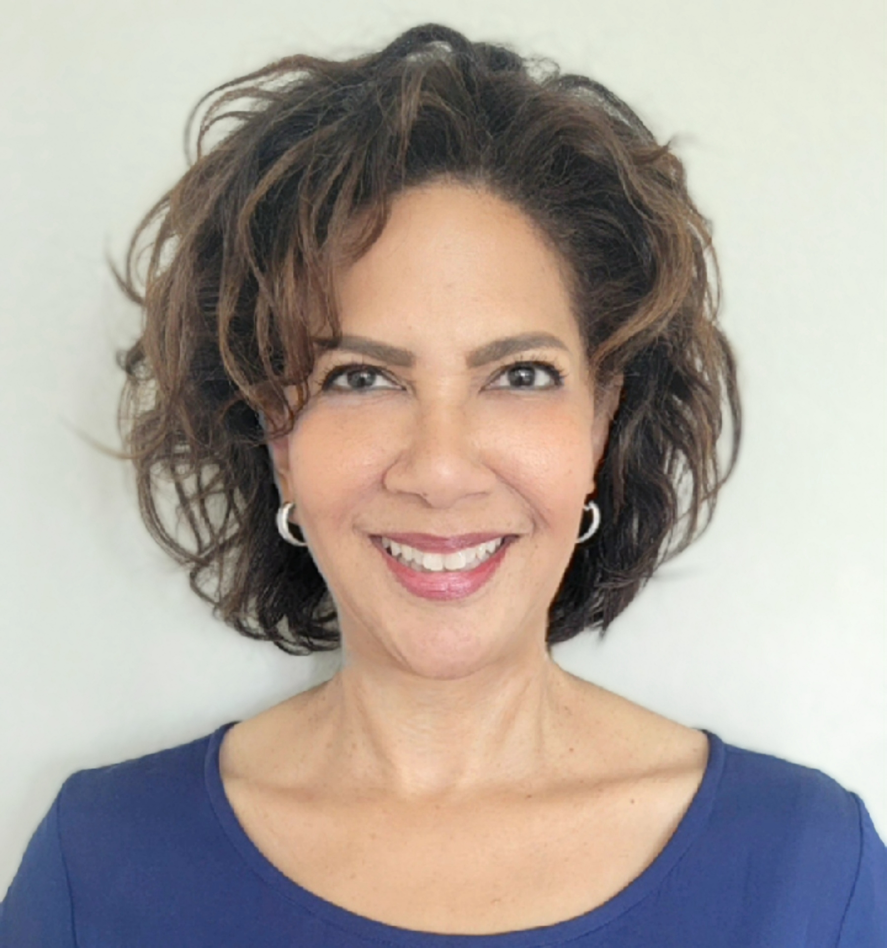 Professional headshot of a smiling woman with shoulder-length dark hair wearing a navy blue top Headshot