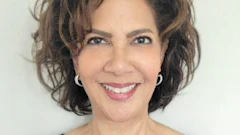 Professional headshot of a smiling woman with shoulder-length dark hair wearing a navy blue top