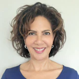 Professional headshot of a smiling woman with shoulder-length dark hair wearing a navy blue top