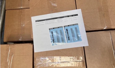 Printed document with data tables placed on stacked cardboard shipping boxes