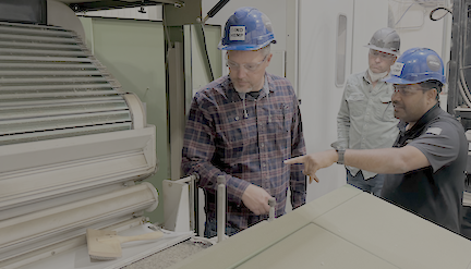 Workers in hard hats examining equipment in an industrial manufacturing facility