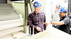 Workers in hard hats examining equipment in an industrial manufacturing facility