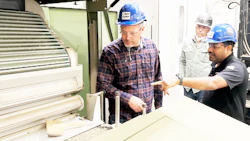 Workers in hard hats examining equipment in an industrial manufacturing facility