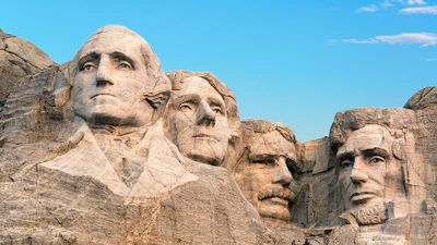 Mount Rushmore monument featuring four carved presidential faces in granite rock against blue sky