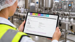 Factory worker in safety gear viewing software dashboard on tablet in industrial manufacturing facility