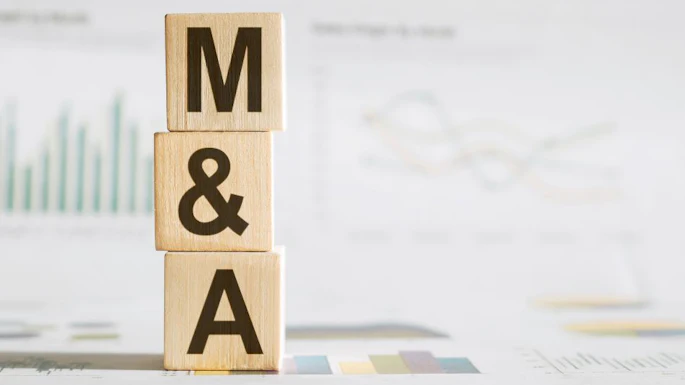 Wooden blocks spelling M&A stacked on business documents with financial charts
