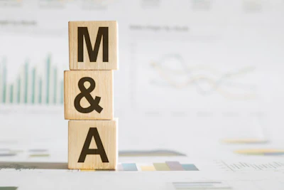 Wooden blocks spelling M&A stacked on business documents with financial charts