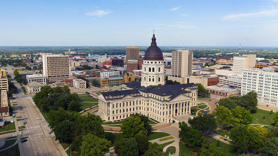 Aerial view of a state capitol building with dome and surrounding government complex in an urban setting