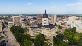 Aerial view of a state capitol building with dome and surrounding government complex in an urban setting