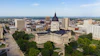 Aerial view of a state capitol building with dome and surrounding government complex in an urban setting