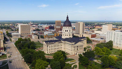 Aerial view of a state capitol building with dome and surrounding government complex in an urban setting