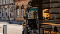 UPS electric delivery truck parked on a historic city street with the company's yellow shield logo visible on the vehicle's side