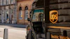 UPS electric delivery truck parked on a historic city street with the company's yellow shield logo visible on the vehicle's side