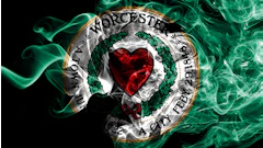 Worcester City Football Club circular emblem with red heart, green wreath, and gold border on black background