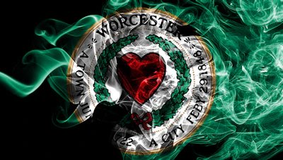 Worcester City Football Club circular emblem with red heart, green wreath, and gold border on black background